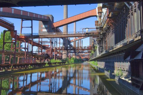 Das große Wasserbecken verwandelt sich im Winter in die 150 Meter lange ZOLLVEREIN® Eisbahn, die zum Freizeitvergnügen in faszinierender Atmosphäre einlädt. Früher wurde das Gleis von den Druckmaschinen befahren, sie hielten an jedem der 304 Koksöfen, öffneten sie und drückten den fertigen Koks heraus. Seit 1999 wird die Kokerei Zollverein mit „Monochromatic Red and Blue“ (1999) von Jonathan Speirs und Mark Major allabendlich zu einem riesigen Lichtkunstwerk.

Die 600 Meter langen Koksofenbatterien mit 304 schmalen Koksöfen prägen das Gesicht der sogenannten „schwarzen Seite“ der Kokerei. Die Ofendecke, das Innere der Koksöfen, die Löschgleishalle und weitere Bereiche können Besucher im Rahmen einer Führung im  Denkmalpfad ZOLLVEREIN® entdecken.

Ort: Areal C [Kokerei], Druckmaschinengleis [C74]