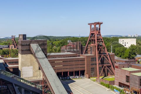 Die Geschichte Zollvereins beginnt in den Pioniertagen des heutigen Ruhrgebiets. Der erste Schacht wurde 1847 abgeteuft, vier Jahre später die erste Kohle gefördert: Vier weitere Anlagen entstanden, die letzte war die Schachtanlage Zollverein XII,  die ab 1932 die Förderung der gesamten Zollverein-Kohle zentral übernahm. 

Die Gebäude der 1928 bis 1932 im Stil der „Neuen Sachlichkeit“ nach Entwürfen der Architekten Fritz Schupp und Martin Kremmer gebauten Anlage sind nach dem Prinzip „Form follows Function“ zum optimalen Ablauf der Kohleförderung und -aufbereitung angeordnet. Trotz Rekordzahlen wie 12.000 Tagestonnen verwertbarer Steinkohle machte das Ende der Schwerindustrie auch vor Zollverein nicht Halt. Am 23. Dezember 1986 fuhr die letzte Schicht ein. An diesem Tag stand die Zeche bereits unter Denkmalschutz, 1990 begannen die Sanierungsarbeiten und seit 2001 sind Zeche und Kokerei Zollverein UNESCO-Welterbe. Mit dem Denkmalpfad ZOLLVEREIN®, dem Ruhr Museum und dem Red Dot Design Museum sind auf Schacht XII drei der beliebtesten Touristenziele der Region angesiedelt. Das Doppelbock-Fördergerüst der Schachtanlage ist heute ein Wahrzeichen für das gesamte Ruhrgebiet. 

Das 55 Meter hohe Doppelbock-Fördergerüst ist das Wahrzeichen der Zeche Zollverein, der Stadt Essen und der gesamten Region: Die als Doppelstrebengerüst in Vollwandbauweise konstruierte Förderanlage ermöglichte eine doppelte Fördermechanik, mittels derer die doppelte Menge Förderwagen bzw. Fördergefäße transportiert werden konnten. Zollverein Schacht XII galt zu Betriebszeiten als die leistungsstärkste Zeche der Welt. 250 Stufen führen auf die oberste Plattform des Gerüstes, deren Seilscheiben sich auch heute noch drehen: Der Schacht wird heute von der RAG AG für die zentrale Wasserhaltung genutzt. 

Als Forum Kohlenwäsche wird der Platz vor der Kohlenwäsche [A14] auf Schacht XII bezeichnet. Im Sommer wird das Forum regelmäßig für Veranstaltungen genutzt.
 
Ort: Areal A [Schacht XII]