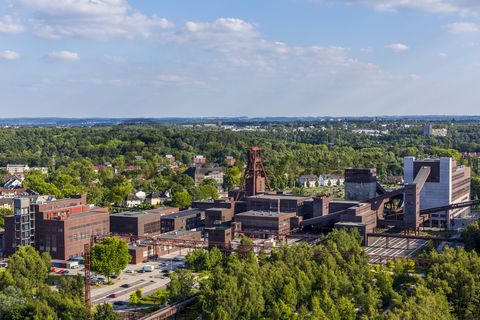 Die Geschichte Zollvereins beginnt in den Pioniertagen des heutigen Ruhrgebiets. Der erste Schacht wurde 1847 abgeteuft, vier Jahre später die erste Kohle gefördert: Vier weitere Anlagen entstanden, die letzte war die Schachtanlage Zollverein XII,  die ab 1932 die Förderung der gesamten Zollverein-Kohle zentral übernahm. 

Die Gebäude der 1928 bis 1932 im Stil der „Neuen Sachlichkeit“ nach Entwürfen der Architekten Fritz Schupp und Martin Kremmer gebauten Anlage sind nach dem Prinzip „Form follows Function“ zum optimalen Ablauf der Kohleförderung und -aufbereitung angeordnet. Trotz Rekordzahlen wie 12.000 Tagestonnen verwertbarer Steinkohle machte das Ende der Schwerindustrie auch vor Zollverein nicht Halt. Am 23. Dezember 1986 fuhr die letzte Schicht ein. An diesem Tag stand die Zeche bereits unter Denkmalschutz, 1990 begannen die Sanierungsarbeiten und seit 2001 sind Zeche und Kokerei Zollverein UNESCO-Welterbe. Mit dem Denkmalpfad ZOLLVEREIN®, dem Ruhr Museum und dem Red Dot Design Museum sind auf Schacht XII drei der beliebtesten Touristenziele der Region angesiedelt. Das Doppelbock-Fördergerüst der Schachtanlage ist heute ein Wahrzeichen für das gesamte Ruhrgebiet. 

Ort: Areal A [Schacht XII]