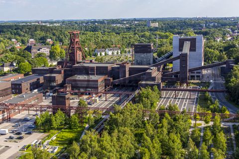 Die Geschichte Zollvereins beginnt in den Pioniertagen des heutigen Ruhrgebiets. Der erste Schacht wurde 1847 abgeteuft, vier Jahre später die erste Kohle gefördert: Vier weitere Anlagen entstanden, die letzte war die Schachtanlage Zollverein XII,  die ab 1932 die Förderung der gesamten Zollverein-Kohle zentral übernahm. 

Die Gebäude der 1928 bis 1932 im Stil der „Neuen Sachlichkeit“ nach Entwürfen der Architekten Fritz Schupp und Martin Kremmer gebauten Anlage sind nach dem Prinzip „Form follows Function“ zum optimalen Ablauf der Kohleförderung und -aufbereitung angeordnet. Trotz Rekordzahlen wie 12.000 Tagestonnen verwertbarer Steinkohle machte das Ende der Schwerindustrie auch vor Zollverein nicht Halt. Am 23. Dezember 1986 fuhr die letzte Schicht ein. An diesem Tag stand die Zeche bereits unter Denkmalschutz, 1990 begannen die Sanierungsarbeiten und seit 2001 sind Zeche und Kokerei Zollverein UNESCO-Welterbe. Mit dem Denkmalpfad ZOLLVEREIN®, dem Ruhr Museum und dem Red Dot Design Museum sind auf Schacht XII drei der beliebtesten Touristenziele der Region angesiedelt. Das Doppelbock-Fördergerüst der Schachtanlage ist heute ein Wahrzeichen für das gesamte Ruhrgebiet. 

Ort: Areal A [Schacht XII]