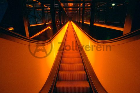 Die beiden 58 Meter langen Rolltreppen an der Kohlenwäsche [A14] befördern die Besucher direkt auf die 24-Meter-Ebene der Kohlenwäsche und von dort wieder nach unten. Die beiden Sonderanfertigungen von ThyssenKrupp Elevator – eine für die Auffahrt, eine für die Abfahrt – orientieren sich an den historischen Bandbrücken. Das Konzept wurde von dem Rotterdamer Office for Metropolitan Architecture (OMA) entwickelt. Eine Fahrt auf einer der beiden höchsten freistehenden Fahrtreppen Deutschlands dauert 90 Sekunden. Highlight: Bei Dunkelheit leuchten die Fahrtreppen orangerot.

Ort: Areal A [Schacht XII], Kohlenwäsche [A14]