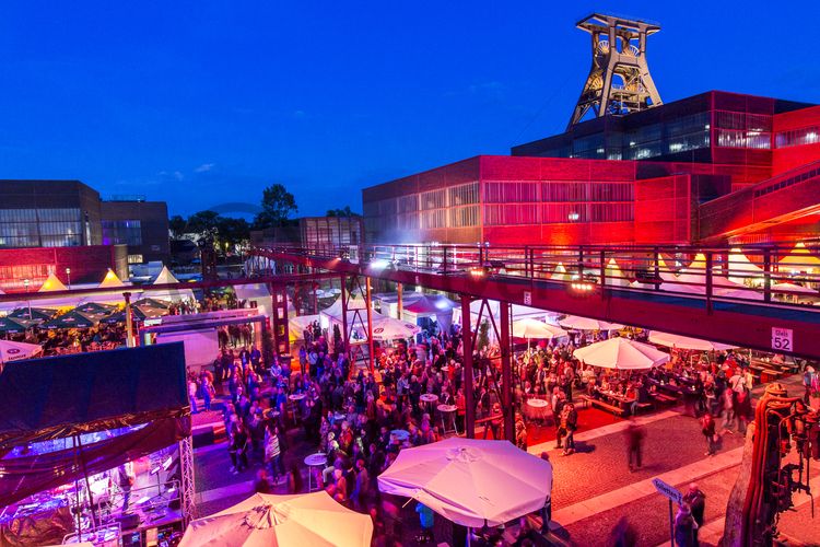 Einmal im Jahr treffen die regionalen Spitzengastronomen zur Gourmet-Meile Metropole Ruhr auf dem ehemaligen Gleisboulevard auf dem UNESCO-Welterbe Zollverein zusammen. Neben einer breiten Vielfalt kulinarischer Verlockungen bietet dieses Event ein anregendes und stimmungsvolles Ambiente für Gäste und Feinschmecker aus der ganzen Region.

Gleisboulevard nennt sich der Platz nördlich der Kohlenwäsche zwischen der Fritz-Schupp-Allee und der Halle 12. Zu Betriebszeiten reihten sich dort die Waggons aneinander, die unter den Produktionsanlagen mit Kohle bzw. Bergematerial beladen wurden. 

Das 55 Meter hohe Doppelbock-Fördergerüst ist das Wahrzeichen der Zeche Zollverein, der Stadt Essen und der gesamten Region: Die als Doppelstrebengerüst in Vollwandbauweise konstruierte Förderanlage ermöglichte eine doppelte Fördermechanik, mittels derer die doppelte Menge Förderwagen bzw. Fördergefäße transportiert werden konnten. Zollverein Schacht XII galt zu Betriebszeiten als die leistungsstärkste Zeche der Welt. 250 Stufen führen auf die oberste Plattform des Gerüstes, deren Seilscheiben sich auch heute noch drehen: Der Schacht wird heute von der RAG AG für die zentrale Wasserhaltung genutzt.

Pause machen im 