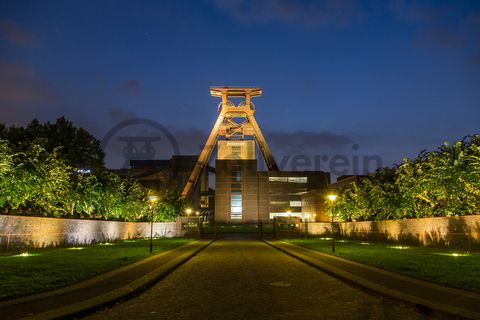 Die Geschichte Zollvereins beginnt in den Pioniertagen des heutigen Ruhrgebiets. Der erste Schacht wurde 1847 abgeteuft, vier Jahre später die erste Kohle gefördert: Vier weitere Anlagen entstanden, die letzte war die Schachtanlage Zollverein XII,  die ab 1932 die Förderung der gesamten Zollverein-Kohle zentral übernahm. 

Die Gebäude der 1928 bis 1932 im Stil der „Neuen Sachlichkeit“ nach Entwürfen der Architekten Fritz Schupp und Martin Kremmer gebauten Anlage sind nach dem Prinzip „Form follows Function“ zum optimalen Ablauf der Kohleförderung und -aufbereitung angeordnet. Trotz Rekordzahlen wie 12.000 Tagestonnen verwertbarer Steinkohle machte das Ende der Schwerindustrie auch vor Zollverein nicht Halt. Am 23. Dezember 1986 fuhr die letzte Schicht ein. An diesem Tag stand die Zeche bereits unter Denkmalschutz, 1990 begannen die Sanierungsarbeiten und seit 2001 sind Zeche und Kokerei Zollverein UNESCO-Welterbe. Mit dem Denkmalpfad ZOLLVEREIN®, dem Ruhr Museum und dem Red Dot Design Museum sind auf Schacht XII drei der beliebtesten Touristenziele der Region angesiedelt. Das Doppelbock-Fördergerüst der Schachtanlage ist heute ein Wahrzeichen für das gesamte Ruhrgebiet. 

Das 55 Meter hohe Doppelbock-Fördergerüst ist das Wahrzeichen der Zeche Zollverein, der Stadt Essen und der gesamten Region: Die als Doppelstrebengerüst in Vollwandbauweise konstruierte Förderanlage ermöglichte eine doppelte Fördermechanik, mittels derer die doppelte Menge Förderwagen bzw. Fördergefäße transportiert werden konnten. Zollverein Schacht XII galt zu Betriebszeiten als die leistungsstärkste Zeche der Welt. 250 Stufen führen auf die oberste Plattform des Gerüstes, deren Seilscheiben sich auch heute noch drehen: Der Schacht wird heute von der RAG AG für die zentrale Wasserhaltung genutzt.

Areal A [Schacht XII], Fördergerüst [A1]