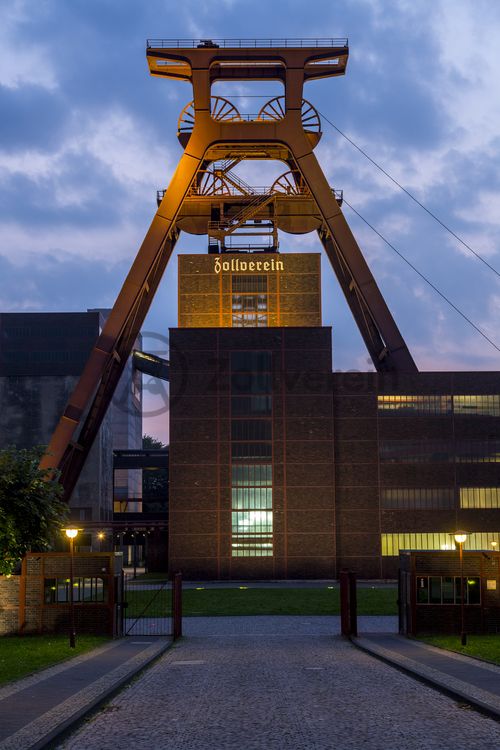 Die Geschichte Zollvereins beginnt in den Pioniertagen des heutigen Ruhrgebiets. Der erste Schacht wurde 1847 abgeteuft, vier Jahre später die erste Kohle gefördert: Vier weitere Anlagen entstanden, die letzte war die Schachtanlage Zollverein XII,  die ab 1932 die Förderung der gesamten Zollverein-Kohle zentral übernahm. 

Die Gebäude der 1928 bis 1932 im Stil der „Neuen Sachlichkeit“ nach Entwürfen der Architekten Fritz Schupp und Martin Kremmer gebauten Anlage sind nach dem Prinzip „Form follows Function“ zum optimalen Ablauf der Kohleförderung und -aufbereitung angeordnet. Trotz Rekordzahlen wie 12.000 Tagestonnen verwertbarer Steinkohle machte das Ende der Schwerindustrie auch vor Zollverein nicht Halt. Am 23. Dezember 1986 fuhr die letzte Schicht ein. An diesem Tag stand die Zeche bereits unter Denkmalschutz, 1990 begannen die Sanierungsarbeiten und seit 2001 sind Zeche und Kokerei Zollverein UNESCO-Welterbe. Mit dem Denkmalpfad ZOLLVEREIN®, dem Ruhr Museum und dem Red Dot Design Museum sind auf Schacht XII drei der beliebtesten Touristenziele der Region angesiedelt. Das Doppelbock-Fördergerüst der Schachtanlage ist heute ein Wahrzeichen für das gesamte Ruhrgebiet. 

Das 55 Meter hohe Doppelbock-Fördergerüst ist das Wahrzeichen der Zeche Zollverein, der Stadt Essen und der gesamten Region: Die als Doppelstrebengerüst in Vollwandbauweise konstruierte Förderanlage ermöglichte eine doppelte Fördermechanik, mittels derer die doppelte Menge Förderwagen bzw. Fördergefäße transportiert werden konnten. Zollverein Schacht XII galt zu Betriebszeiten als die leistungsstärkste Zeche der Welt. 250 Stufen führen auf die oberste Plattform des Gerüstes, deren Seilscheiben sich auch heute noch drehen: Der Schacht wird heute von der RAG AG für die zentrale Wasserhaltung genutzt.

Areal A [Schacht XII], Fördergerüst [A1]