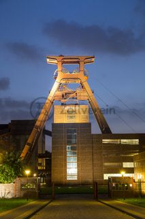 Die Geschichte Zollvereins beginnt in den Pioniertagen des heutigen Ruhrgebiets. Der erste Schacht wurde 1847 abgeteuft, vier Jahre später die erste Kohle gefördert: Vier weitere Anlagen entstanden, die letzte war die Schachtanlage Zollverein XII,  die ab 1932 die Förderung der gesamten Zollverein-Kohle zentral übernahm. 

Die Gebäude der 1928 bis 1932 im Stil der „Neuen Sachlichkeit“ nach Entwürfen der Architekten Fritz Schupp und Martin Kremmer gebauten Anlage sind nach dem Prinzip „Form follows Function“ zum optimalen Ablauf der Kohleförderung und -aufbereitung angeordnet. Trotz Rekordzahlen wie 12.000 Tagestonnen verwertbarer Steinkohle machte das Ende der Schwerindustrie auch vor Zollverein nicht Halt. Am 23. Dezember 1986 fuhr die letzte Schicht ein. An diesem Tag stand die Zeche bereits unter Denkmalschutz, 1990 begannen die Sanierungsarbeiten und seit 2001 sind Zeche und Kokerei Zollverein UNESCO-Welterbe. Mit dem Denkmalpfad ZOLLVEREIN®, dem Ruhr Museum und dem Red Dot Design Museum sind auf Schacht XII drei der beliebtesten Touristenziele der Region angesiedelt. Das Doppelbock-Fördergerüst der Schachtanlage ist heute ein Wahrzeichen für das gesamte Ruhrgebiet. 

Das 55 Meter hohe Doppelbock-Fördergerüst ist das Wahrzeichen der Zeche Zollverein, der Stadt Essen und der gesamten Region: Die als Doppelstrebengerüst in Vollwandbauweise konstruierte Förderanlage ermöglichte eine doppelte Fördermechanik, mittels derer die doppelte Menge Förderwagen bzw. Fördergefäße transportiert werden konnten. Zollverein Schacht XII galt zu Betriebszeiten als die leistungsstärkste Zeche der Welt. 250 Stufen führen auf die oberste Plattform des Gerüstes, deren Seilscheiben sich auch heute noch drehen: Der Schacht wird heute von der RAG AG für die zentrale Wasserhaltung genutzt.

Areal A [Schacht XII], Fördergerüst [A1]