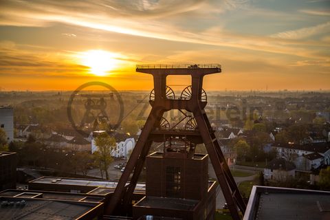 Die Geschichte Zollvereins beginnt in den Pioniertagen des heutigen Ruhrgebiets. Der erste Schacht wurde 1847 abgeteuft, vier Jahre später die erste Kohle gefördert: Vier weitere Anlagen entstanden, die letzte war die Schachtanlage Zollverein XII,  die ab 1932 die Förderung der gesamten Zollverein-Kohle zentral übernahm. 

Die Gebäude der 1928 bis 1932 im Stil der „Neuen Sachlichkeit“ nach Entwürfen der Architekten Fritz Schupp und Martin Kremmer gebauten Anlage sind nach dem Prinzip „Form follows Function“ zum optimalen Ablauf der Kohleförderung und -aufbereitung angeordnet. Trotz Rekordzahlen wie 12.000 Tagestonnen verwertbarer Steinkohle machte das Ende der Schwerindustrie auch vor Zollverein nicht Halt. Am 23. Dezember 1986 fuhr die letzte Schicht ein. An diesem Tag stand die Zeche bereits unter Denkmalschutz, 1990 begannen die Sanierungsarbeiten und seit 2001 sind Zeche und Kokerei Zollverein UNESCO-Welterbe. Mit dem Denkmalpfad ZOLLVEREIN®, dem Ruhr Museum und dem Red Dot Design Museum sind auf Schacht XII drei der beliebtesten Touristenziele der Region angesiedelt. Das Doppelbock-Fördergerüst der Schachtanlage ist heute ein Wahrzeichen für das gesamte Ruhrgebiet. 

Das 55 Meter hohe Doppelbock-Fördergerüst ist das Wahrzeichen der Zeche Zollverein, der Stadt Essen und der gesamten Region: Die als Doppelstrebengerüst in Vollwandbauweise konstruierte Förderanlage ermöglichte eine doppelte Fördermechanik, mittels derer die doppelte Menge Förderwagen bzw. Fördergefäße transportiert werden konnten. Zollverein Schacht XII galt zu Betriebszeiten als die leistungsstärkste Zeche der Welt. 250 Stufen führen auf die oberste Plattform des Gerüstes, deren Seilscheiben sich auch heute noch drehen: Der Schacht wird heute von der RAG AG für die zentrale Wasserhaltung genutzt.

Areal A [Schacht XII], Fördergerüst [A1]