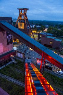 Seit der ersten ExtraSchicht im Jahr 2001 richtet die „Nacht der Industriekultur“ alljährlich ihr Rampenlicht auf die aktuellen und ehemaligen Stätten industrieller Arbeit im Ruhrgebiet. Das UNESCO-Welterbe Zollverein ist seit der ersten Stunde ein wichtiger Spielort für das Veranstaltungshighlight. Die Besucher auf Zollverein erwartet zwischen 18 Uhr und 2 Uhr nachts ein bunter Veranstaltungsmix mit vielen interaktiven Kulturangeboten, Ausstellungen, Musikbeiträgen, Licht- und Kunstinstallationen, Walk Acts und internationalen Straßentheaterinszenierungen. 

Das 55 Meter hohe Doppelbock-Fördergerüst ist das Wahrzeichen der Zeche Zollverein, der Stadt Essen und der gesamten Region: Die als Doppelstrebengerüst in Vollwandbauweise konstruierte Förderanlage ermöglichte eine doppelte Fördermechanik. Dadurch konnte die doppelte Menge an Förderwagen bzw. Fördergefäßen transportiert werden. Zollverein Schacht XII galt zu Betriebszeiten als die leistungsstärkste Zeche der Welt. 250 Stufen führen auf die oberste Plattform des Gerüstes, deren Seilscheiben sich auch heute noch manchmal drehen: Der Schacht wird von der RAG AG für die zentrale Wasserhaltung genutzt.

Areal A [Schacht XII], Fördergerüst [A1]

Das größte Übertagegebäude auf Zollverein, die Kohlenwäsche [A14], war zu Betriebszeiten eine Riesenmaschine: Täglich wurden dort 23.000 Tonnen Rohkohle sortiert und klassiert. Von 2003 bis 2006 wurde die Kohlenwäsche vom Office for Metropolitan Architecture (OMA) unter Leitung von Rem Koolhaas und dem Essener Büro Böll & Krabel umfassend saniert und für die spätere Nutzung vorbereitet. 

Eine 58 Meter lange Rolltreppe bringt die Besucher heute direkt in das RUHR.VISITORCENTER Essen auf der 24-Meter-Ebene. 2010 eröffnete das Ruhr Museum in der Kohlenwäsche, das in drei Etagen eine Dauerausstellung zu den Kategorien Gegenwart – Gedächtnis – Geschichte präsentiert. Die oberen Etagen gehören mit den authentisch erhaltenen Übertageanlagen zum Denkmalpfad ZOLLVEREIN®. Auf dem Dach der Kohlenwäsche sind zwei Aussichtsplattformen installiert, die einen Rundblick auf das Gelände und die Region bieten. Das Portal der Industriekultur informiert über industriekulturelle Angebote im Ruhrgebiet und in Nordrhein-Westfalen.

Areal A [Schacht XII], Kohlenwäsche [A14]