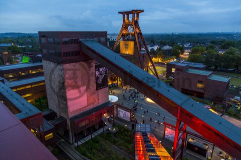 Seit der ersten ExtraSchicht im Jahr 2001 richtet die „Nacht der Industriekultur“ alljährlich ihr Rampenlicht auf die aktuellen und ehemaligen Stätten industrieller Arbeit im Ruhrgebiet. Das UNESCO-Welterbe Zollverein ist seit der ersten Stunde ein wichtiger Spielort für das Veranstaltungshighlight. Die Besucher auf Zollverein erwartet zwischen 18 Uhr und 2 Uhr nachts ein bunter Veranstaltungsmix mit vielen interaktiven Kulturangeboten, Ausstellungen, Musikbeiträgen, Licht- und Kunstinstallationen, Walk Acts und internationalen Straßentheaterinszenierungen. 

Das 55 Meter hohe Doppelbock-Fördergerüst ist das Wahrzeichen der Zeche Zollverein, der Stadt Essen und der gesamten Region: Die als Doppelstrebengerüst in Vollwandbauweise konstruierte Förderanlage ermöglichte eine doppelte Fördermechanik. Dadurch konnte die doppelte Menge an Förderwagen bzw. Fördergefäßen transportiert werden. Zollverein Schacht XII galt zu Betriebszeiten als die leistungsstärkste Zeche der Welt. 250 Stufen führen auf die oberste Plattform des Gerüstes, deren Seilscheiben sich auch heute noch manchmal drehen: Der Schacht wird von der RAG AG für die zentrale Wasserhaltung genutzt.

Areal A [Schacht XII], Fördergerüst [A1]

Das größte Übertagegebäude auf Zollverein, die Kohlenwäsche [A14], war zu Betriebszeiten eine Riesenmaschine: Täglich wurden dort 23.000 Tonnen Rohkohle sortiert und klassiert. Von 2003 bis 2006 wurde die Kohlenwäsche vom Office for Metropolitan Architecture (OMA) unter Leitung von Rem Koolhaas und dem Essener Büro Böll & Krabel umfassend saniert und für die spätere Nutzung vorbereitet. 

Eine 58 Meter lange Rolltreppe bringt die Besucher heute direkt in das RUHR.VISITORCENTER Essen auf der 24-Meter-Ebene. 2010 eröffnete das Ruhr Museum in der Kohlenwäsche, das in drei Etagen eine Dauerausstellung zu den Kategorien Gegenwart – Gedächtnis – Geschichte präsentiert. Die oberen Etagen gehören mit den authentisch erhaltenen Übertageanlagen zum Denkmalpfad ZOLLVEREIN®. Auf dem Dach der Kohlenwäsche sind zwei Aussichtsplattformen installiert, die einen Rundblick auf das Gelände und die Region bieten. Das Portal der Industriekultur informiert über industriekulturelle Angebote im Ruhrgebiet und in Nordrhein-Westfalen.

Areal A [Schacht XII], Kohlenwäsche [A14]