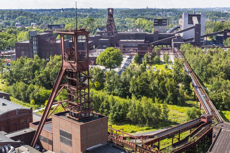 Die Geschichte Zollvereins beginnt in den Pioniertagen des heutigen Ruhrgebiets. Der erste Schacht wurde 1847 abgeteuft, d.h. in die Erde getrieben. Vier Jahre später wurde die erste Kohle gefördert. Im Laufe der Zeit entstanden vier weitere Schachtanlagen. Die letzte war die neue Zentralschachtanlage Zollverein XII, die ab 1932 die gesamte Zollverein-Kohle förderte. 

Noch heute besticht die symmetrische Anordnung der Gebäude auf zwei Blickachsen. Die komplett erhaltenen 20 Einzelgebäude bilden die technischen Arbeits- und Produktionsabläufe nach dem Prinzip „form follows function“ ab. Durchgestaltet bis in die Details der Lampen, Treppengeländer und Türgriffe, ist die Anlage ein komplett erhaltenes Gesamtkunstwerk. Die authentisch erhaltenen Anlagen repräsentieren exemplarisch die soziale, ökonomische, ästhetische und industrielle Geschichte des Kohle- und Stahlzeitalters. 

Trotz Rekordzahlen wie 12.000 Tagestonnen verwertbarer Steinkohle machte das Ende der Schwerindustrie auch vor Zollverein nicht Halt. Am 23. Dezember 1986 fuhr die letzte Schicht ein. An diesem Tag stand die Zeche bereits unter Denkmalschutz, 1990 begannen die Sanierungsarbeiten, seit 2001 sind Zeche und Kokerei Zollverein UNESCO-Welterbe. Mit dem Denkmalpfad ZOLLVEREIN®, dem Ruhr Museum und dem Red Dot Design Museum sind auf Schacht XII drei der beliebtesten Touristenziele der Region. Das Doppelbock-Fördergerüst der Schachtanlage ist heute Wahrzeichen für das gesamte Ruhrgebiet. 

Areal A [Schacht XII]

Der Förderturm und das Einstrebenfördergerüst wurden über den beiden ersten Zollverein-Schächten errichtet. 1904 und 1954 wurde die Schachtanlage modernisiert, auch die Förderanlagen wurden dabei erneuert.
Areal B [Schacht 1/2/8], Fördergerüst [B40]

Areal B [Schacht 1/2/8], Förderturm [B41]