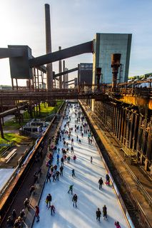 Das große Wasserbecken am ehemaligen Druckmaschinengleis [C74] auf der Kokerei Zollverein verwandelt sich im Winter in die 150 Meter lange ZOLLVEREIN® Eisbahn, die zum Freizeitvergnügen in faszinierender Atmosphäre einlädt. Allabendlich wird die Fläche mit der Installation „Monochromatic Red and Blue“ (1999) von Jonathan Speirs und Mark Major zu einem beeindruckenden Lichtkunstwerk.

Areal C [Kokerei], Druckmaschinengleis [C74], Kokereiallee, 45141 Essen

Die Kokerei Zollverein wurde von 1957 bis 1961 nach Plänen des Architekten Fritz Schupp gebaut, nach Erweiterungsarbeiten war sie ab 1973 die größte Zentralkokerei Europas. Täglich waren bis zu 1.000 Koker rund um die Uhr im Einsatz, bis zu 8.600 Tonnen Koks wurden pro Tag produziert. 1993 wurde die Kokerei stillgelegt, im Jahr 2000 in die Denkmalliste der Stadt Essen aufgenommen, seit 2001 gehört sie zum UNESCO-Welterbe. 2010 ist die Kokerei in den Besitz der Stiftung Zollverein übergegangen. Die „schwarze Seite“ der Kokerei, die den Bereich der Koksproduktion bezeichnet, kann bei einer Führung durch den Denkmalpfad ZOLLVEREIN® besichtigt werden.