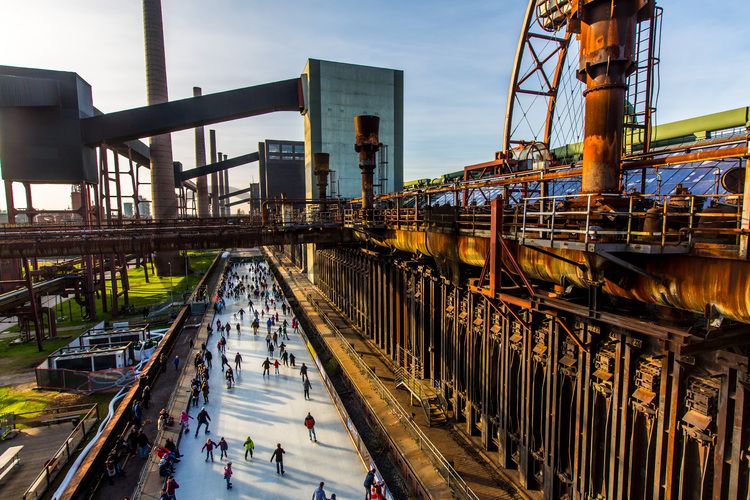 Das große Wasserbecken am ehemaligen Druckmaschinengleis [C74] auf der Kokerei Zollverein verwandelt sich im Winter in die 150 Meter lange ZOLLVEREIN® Eisbahn, die zum Freizeitvergnügen in faszinierender Atmosphäre einlädt. Allabendlich wird die Fläche mit der Installation „Monochromatic Red and Blue“ (1999) von Jonathan Speirs und Mark Major zu einem beeindruckenden Lichtkunstwerk.

Areal C [Kokerei], Druckmaschinengleis [C74], Kokereiallee, 45141 Essen

Die Kokerei Zollverein wurde von 1957 bis 1961 nach Plänen des Architekten Fritz Schupp gebaut, nach Erweiterungsarbeiten war sie ab 1973 die größte Zentralkokerei Europas. Täglich waren bis zu 1.000 Koker rund um die Uhr im Einsatz, bis zu 8.600 Tonnen Koks wurden pro Tag produziert. 1993 wurde die Kokerei stillgelegt, im Jahr 2000 in die Denkmalliste der Stadt Essen aufgenommen, seit 2001 gehört sie zum UNESCO-Welterbe. 2010 ist die Kokerei in den Besitz der Stiftung Zollverein übergegangen. Die „schwarze Seite“ der Kokerei, die den Bereich der Koksproduktion bezeichnet, kann bei einer Führung durch den Denkmalpfad ZOLLVEREIN® besichtigt werden.