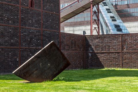 Die Skulptur „Konstellation D4“ des Münchner Bildhauers Alf Lechner (*1925) befindet sich auf der Wiese vor Halle 4 [A4] in unmittelbarer Nähe zum Doppelbock-Fördergerüst. Die 16 Tonnen schwere Arbeit aus Schmiedestahl steht quer zur rechtwinkligen Anordnung der Zechengebäude und spielt mit dem streng geometrischen Grundriss der Anlage. 

Das südliche Fördermaschinenhaus [A4] beherbergte zu Betriebszeiten der Zeche eine der insgesamt zwei Fördermaschinen der Schachtanlage Zollverein XII. Nach der Dach- und Fachsanierung wird es für eine Gastronomie mit Veranstaltungsraum umgebaut.

Areal A [Schacht XII], Halle 4 [A4]

Die 90-sekündige Fahrt auf der Rolltreppe bietet fantastische Ausblicke und führt direkt auf die 24-Meter-Ebene der Kohlenwäsche [A14] mit dem Besucherzentrum. Dort befindet sich auch der Eingang in das Ruhr Museum und der Treffpunkt der Führungen im Denkmalpfad ZOLLVEREIN®.

Areal A [Schacht XII], Kohlenwäsche [A14]