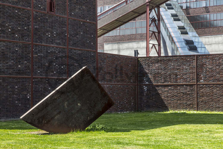 Tonnenschwer und unscheinbar ruht Alf Lechners Skulptur „Konstellation D4“ auf der Wiese vor der Halle 4 in unmittelbarer Nähe des berühmten Doppelbock-Fördergerüsts. Die Skulptur aus der Werkgruppe „Konstellation D1–D8“ steht in einem Winkel von 45 Grad zum rechteckigen Grundriss der Zechengebäude. Sie durchbricht die beiden Achsen, an denen die Anlagen ausgerichtet sind und lenkt den Blick des Betrachters dadurch fast automatisch in Richtung des Doppelbock-Fördergerüsts.

Das südliche Fördermaschinenhaus beherbergte zu Betriebszeiten der Zeche eine der insgesamt zwei Fördermaschinen der Schachtanlage Zollverein XII. Nach der Dach- und Fachsanierung wird es für eine Gastronomie mit Veranstaltungsraum umgebaut.
Halle 4 / The Mine, UNESCO-Welterbe Zollverein, Essen