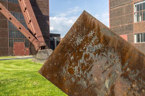 Tonnenschwer und unscheinbar ruht Alf Lechners Skulptur „Konstellation D4“ auf der Wiese vor der Halle 4 in unmittelbarer Nähe des berühmten Doppelbock-Fördergerüsts. Die Skulptur aus der Werkgruppe „Konstellation D1–D8“ steht in einem Winkel von 45 Grad zum rechteckigen Grundriss der Zechengebäude. Sie durchbricht die beiden Achsen, an denen die Anlagen ausgerichtet sind und lenkt den Blick des Betrachters dadurch fast automatisch in Richtung des Doppelbock-Fördergerüsts.

Das südliche Fördermaschinenhaus beherbergte zu Betriebszeiten der Zeche eine der insgesamt zwei Fördermaschinen der Schachtanlage Zollverein XII. Nach der Dach- und Fachsanierung wird es für eine Gastronomie mit Veranstaltungsraum umgebaut.
Halle 4 / The Mine, UNESCO-Welterbe Zollverein, Essen