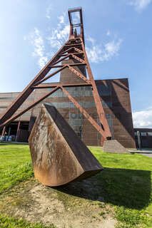 Tonnenschwer und unscheinbar ruht Alf Lechners Skulptur „Konstellation D4“ auf der Wiese vor der Halle 4 in unmittelbarer Nähe des berühmten Doppelbock-Fördergerüsts. Die Skulptur aus der Werkgruppe „Konstellation D1–D8“ steht in einem Winkel von 45 Grad zum rechteckigen Grundriss der Zechengebäude. Sie durchbricht die beiden Achsen, an denen die Anlagen ausgerichtet sind und lenkt den Blick des Betrachters dadurch fast automatisch in Richtung des Doppelbock-Fördergerüsts.

Das südliche Fördermaschinenhaus beherbergte zu Betriebszeiten der Zeche eine der insgesamt zwei Fördermaschinen der Schachtanlage Zollverein XII. Nach der Dach- und Fachsanierung wird es für eine Gastronomie mit Veranstaltungsraum umgebaut.
Halle 4 / The Mine, UNESCO-Welterbe Zollverein, Essen