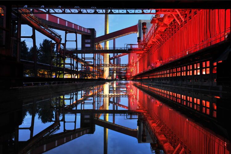 Jede Nacht verwandelt sich die Kokerei Zollverein seit 1999 in ein Kunstwerk, wenn mit Einbruch der Dämmerung die Lichtinstallation „Monochromatic Red and Blue“ von Jonathan Speirs und Mark Major Teile der stillgelegten Anlagen in rotes und blaues Licht taucht.

Die 600 Meter langen Koksofenbatterien mit 304 schmalen Koksöfen gehören zu der sogenannten „schwarzen Seite“ der Kokerei. Dort wurden von 1961 bis 1993 rund um die Uhr täglich 12.000 Tonnen Kohle zu Koks „gebacken“. Besucher können diesen Teil der Anlage im Rahmen einer Führung des Denkmalpfads Zollverein erkunden.
Koksofenbatterien, UNESCO-Welterbe Zollverein